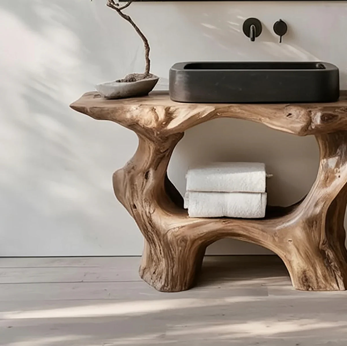 Live edge solid wood bathroom vanity with organic shape, black stone sink, and folded towels