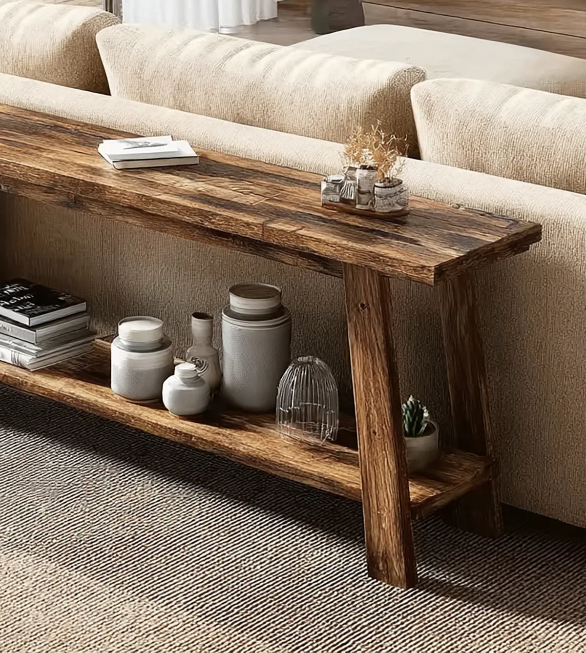 Rustic wooden console table behind beige upholstered sofa with books, jars, and plants on shelves
