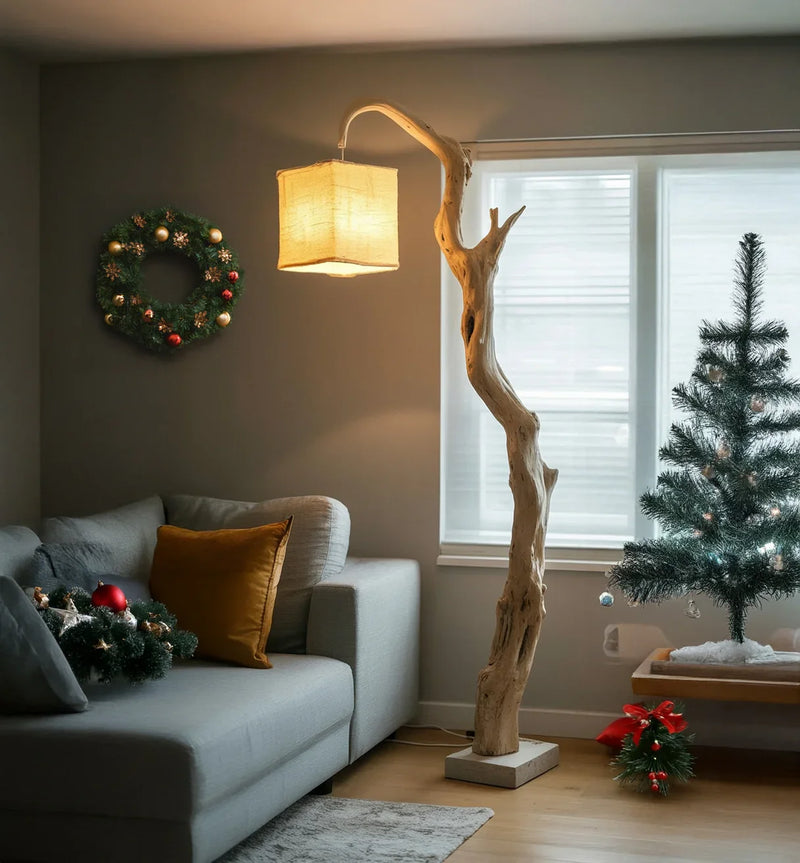 Cozy living room with modern gray sofa, Christmas wreath, rustic wooden floor lamp, and small decorated Christmas tree