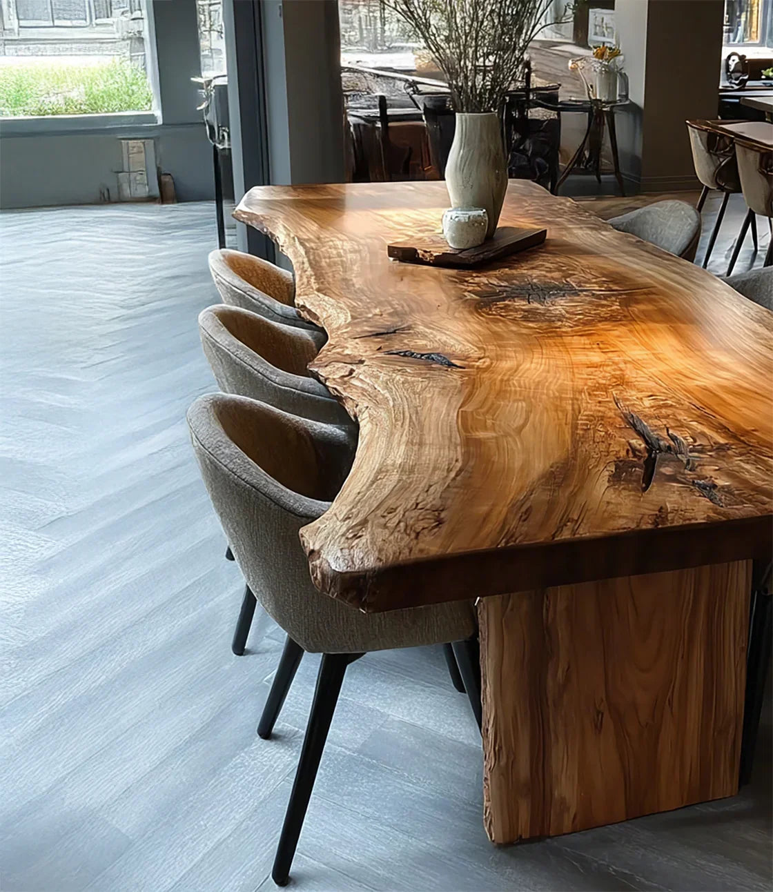 Natural wood live edge dining table with beige upholstered chairs in modern open space