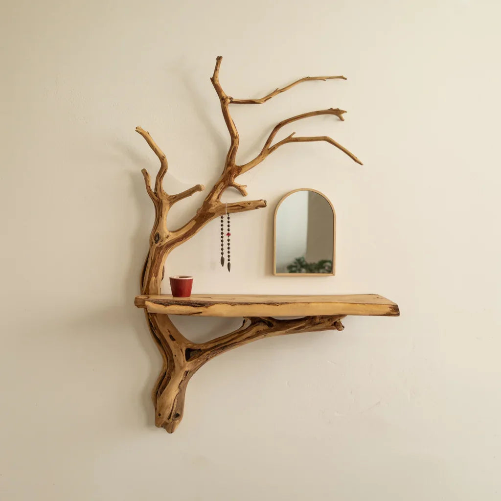 Live edge wood floating shelf with tree branch design, wall mirror, and small red cup.