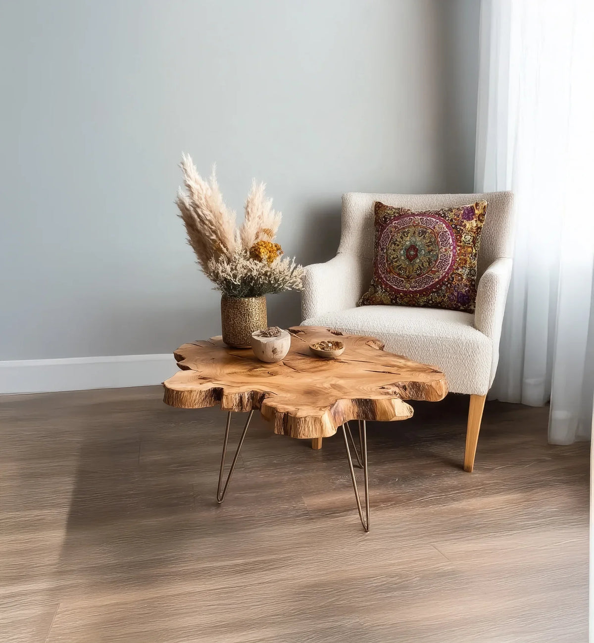 Cozy corner with a white armchair, decorative patterned pillow, and rustic wooden coffee table with dried floral arrangement
