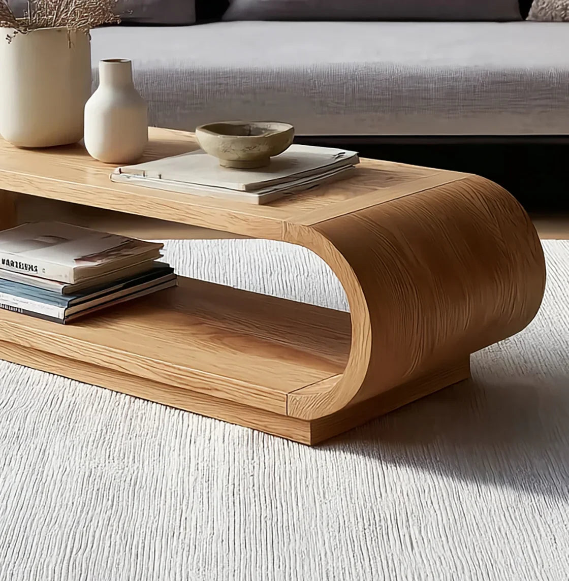 Curved wooden coffee table with vases, bowl, and magazines in modern living room