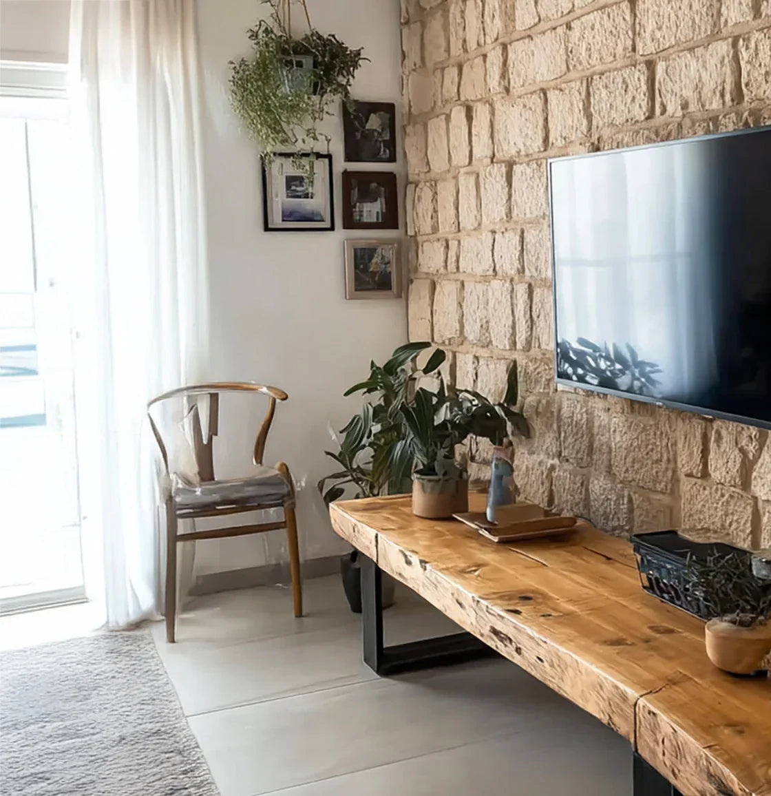 Modern living room with natural stone wall, wooden bench, mounted TV, and indoor plants