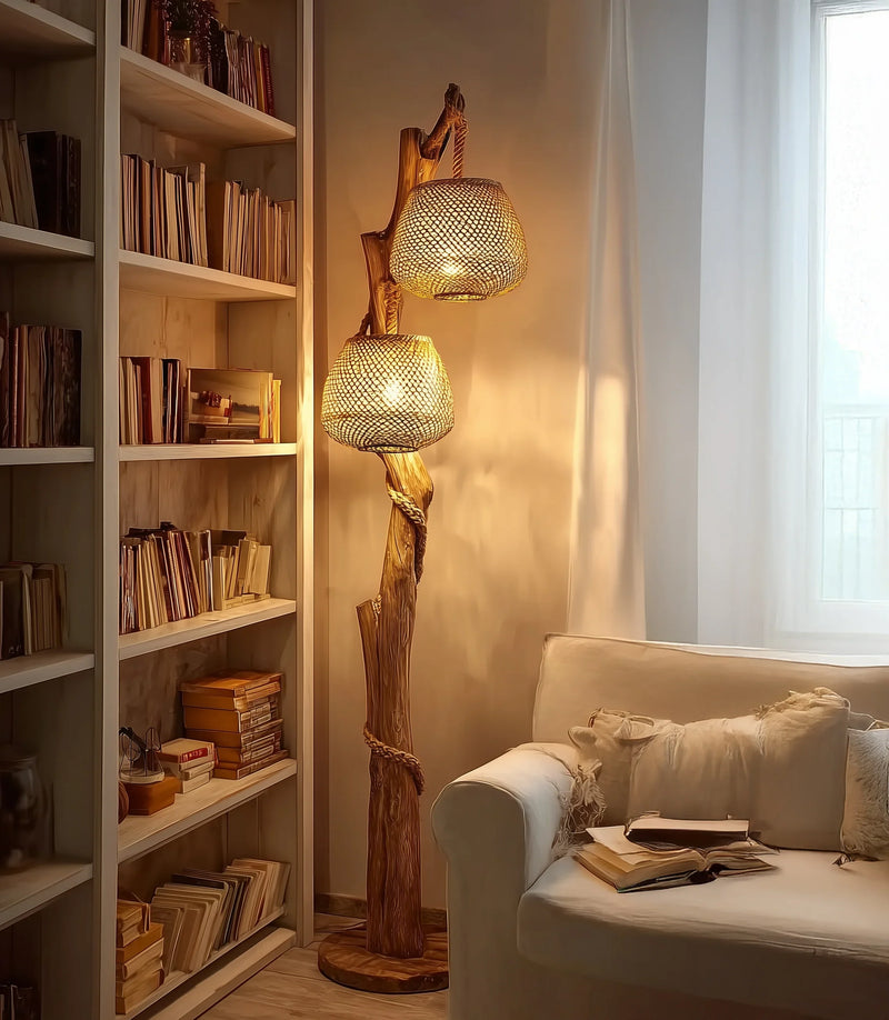 Solid wood sculpted floor lamp with woven rattan shades beside a bookshelf and sofa in cozy living room.