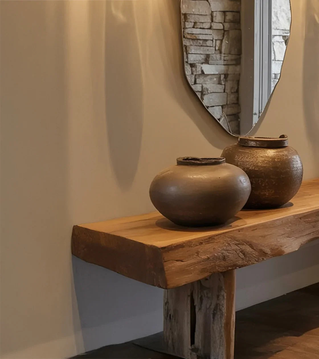Rustic wooden bench with two decorative pottery vases under irregular-shaped wall mirror