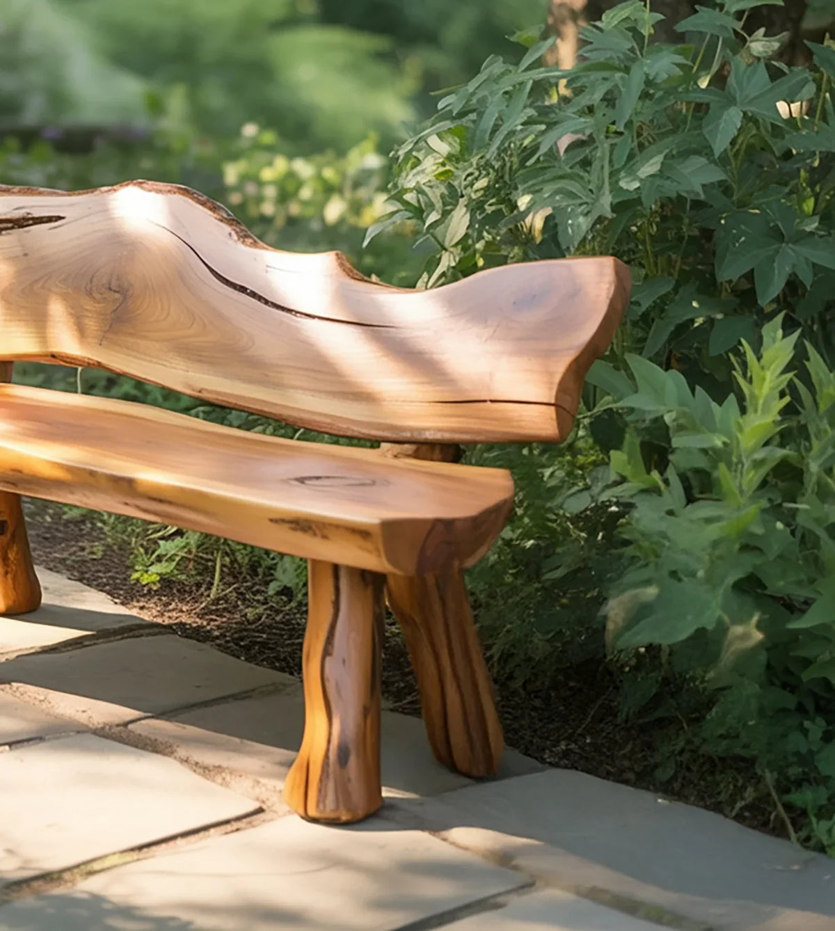 Natural wood garden bench on stone path surrounded by green leafy plants in sunlight
