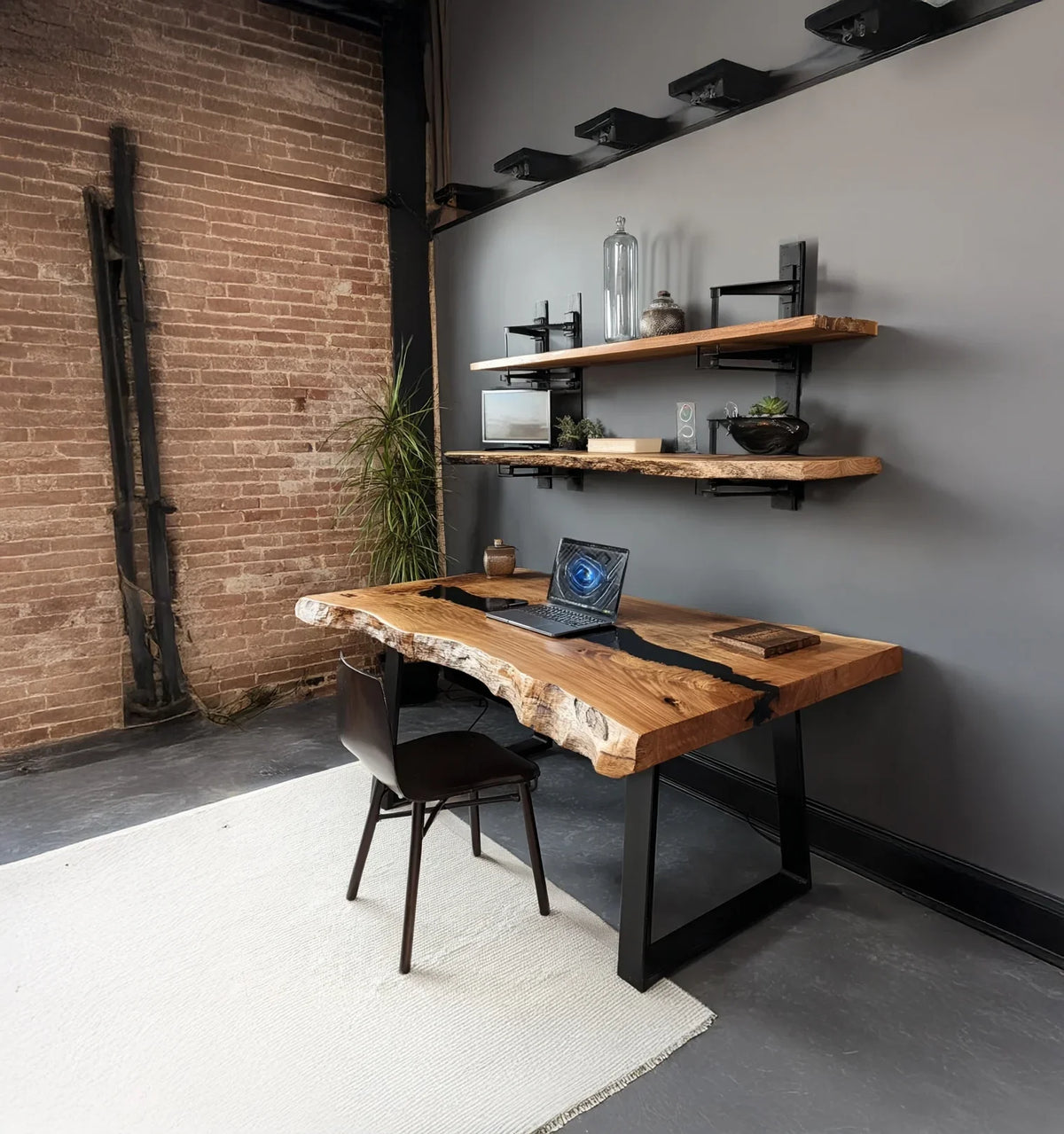 Modern rustic office with live edge wooden desk, black metal legs, laptop, and floating shelves on gray wall