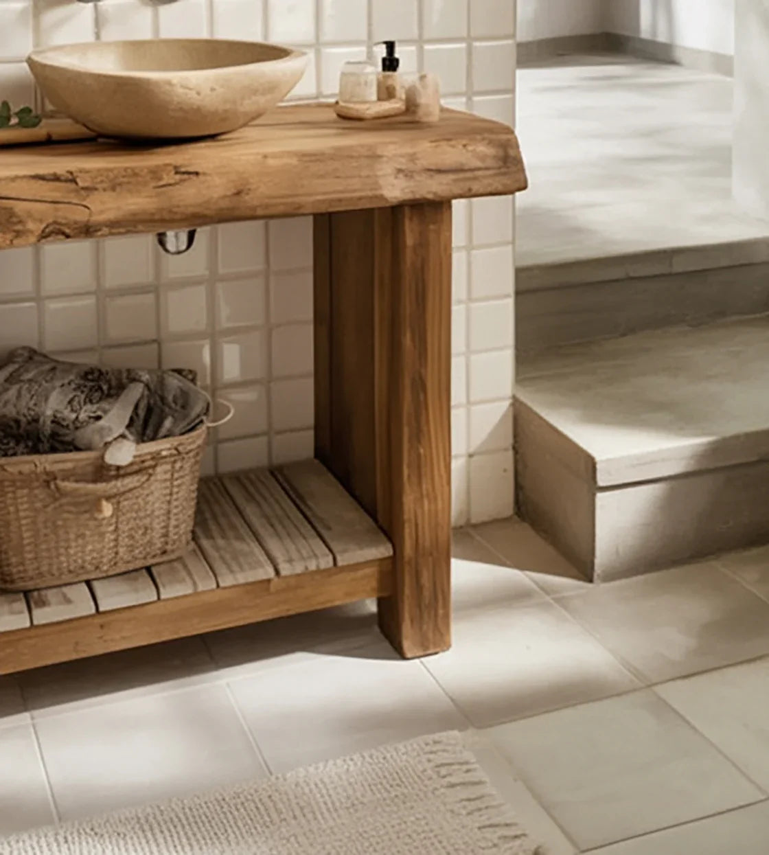 Bathroom with rustic wooden vanity, stone basin sink, wicker basket with towels, and beige tiled floor