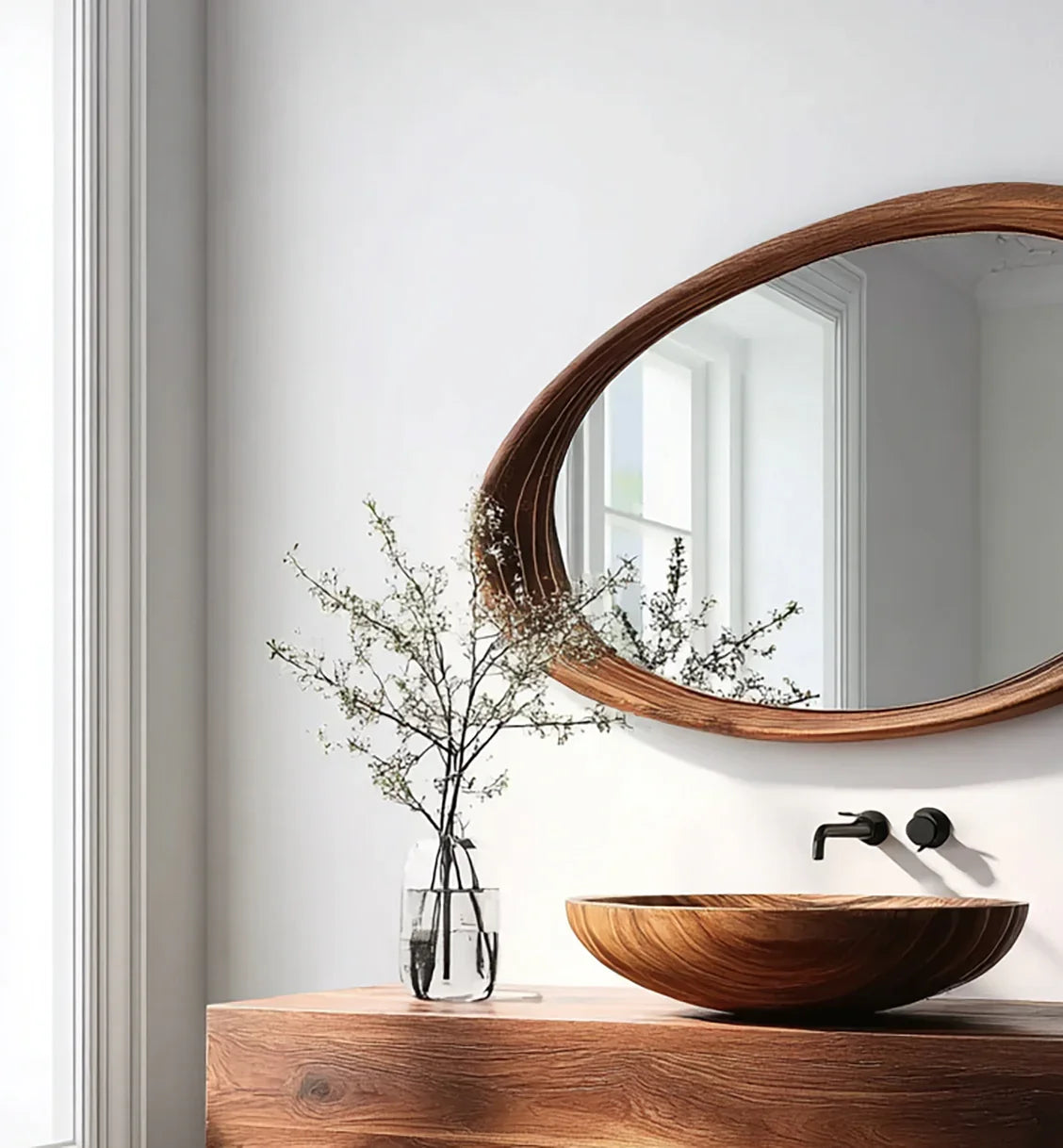 Modern bathroom with a wooden oval mirror, wood grain sink, and glass vase with branches