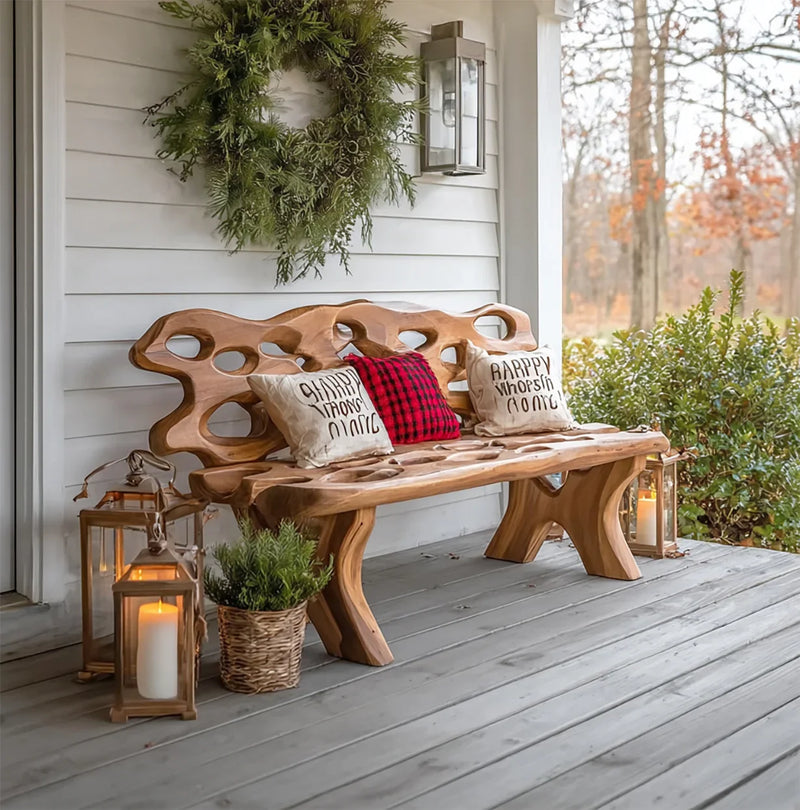 Rustic wooden bench on porch with holiday pillows, green wreath, lanterns, and potted plant