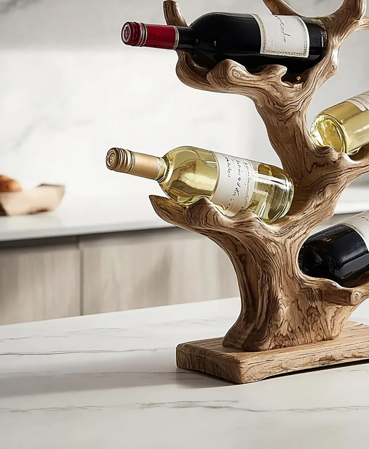 Rustic wooden wine bottle holder shaped like a tree branch with red and white wine bottles on marble countertop