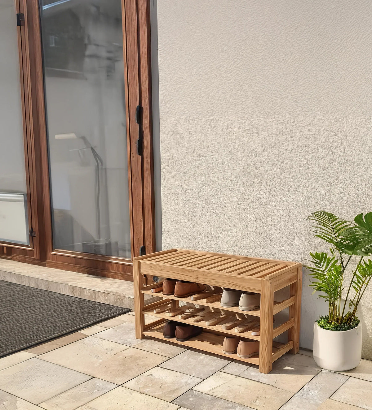 Solid wood bench shoe rack with multiple shelves, placed outdoors on a tiled patio next to a plant.