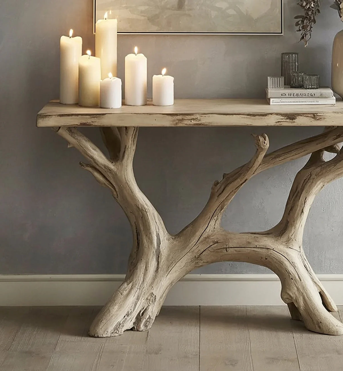 Natural wood console table with branch-like base, decorated with lit pillar candles and books