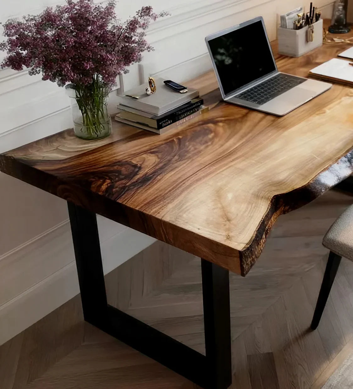 Live edge solid wood desk with metal legs, laptop, books, and a vase of flowers in home office