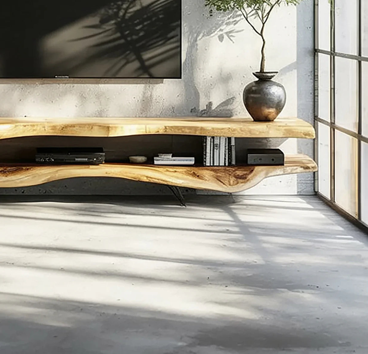 Live edge solid wood TV stand holding books, electronics, and a potted plant in a modern room