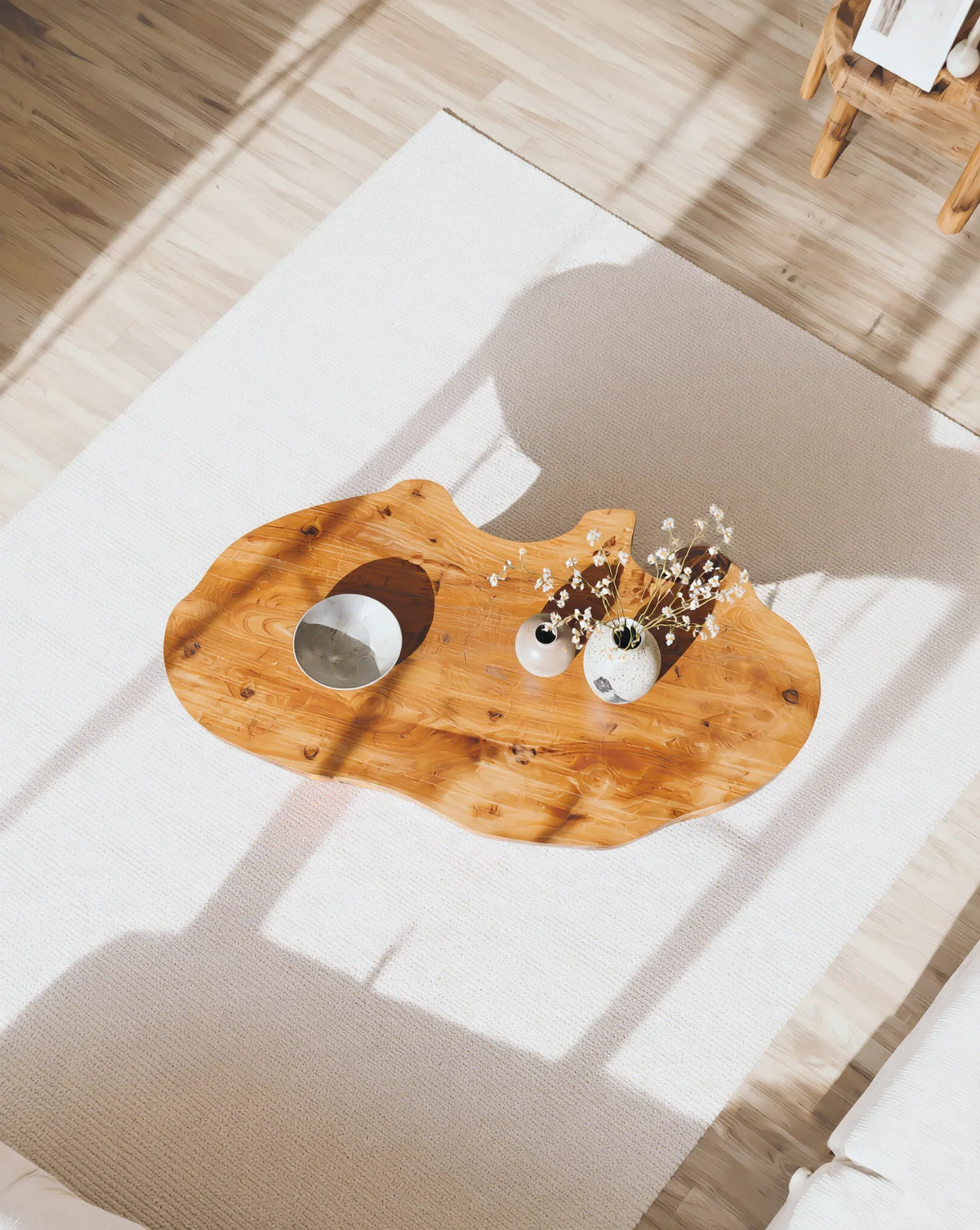 Live edge solid wood coffee table on white rug, decorated with vases in sunlit room