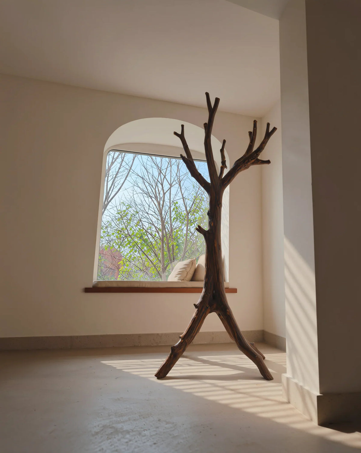 Sustainably crafted solid wood tree bookshelf in a sunlit minimalist room by a window seat.