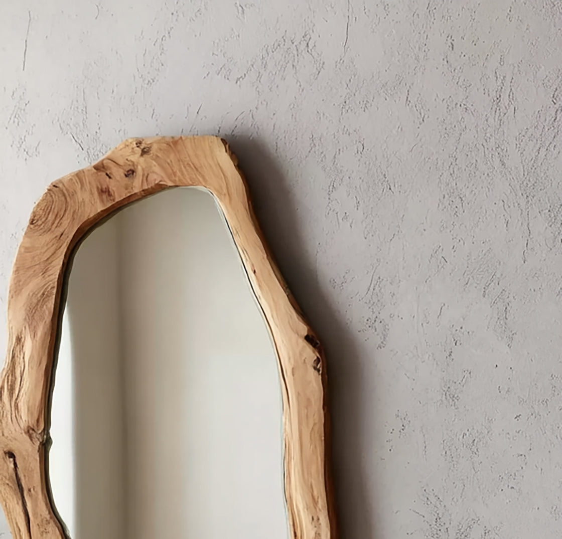 Decorative mirror with a natural wood frame hanging on textured gray wall