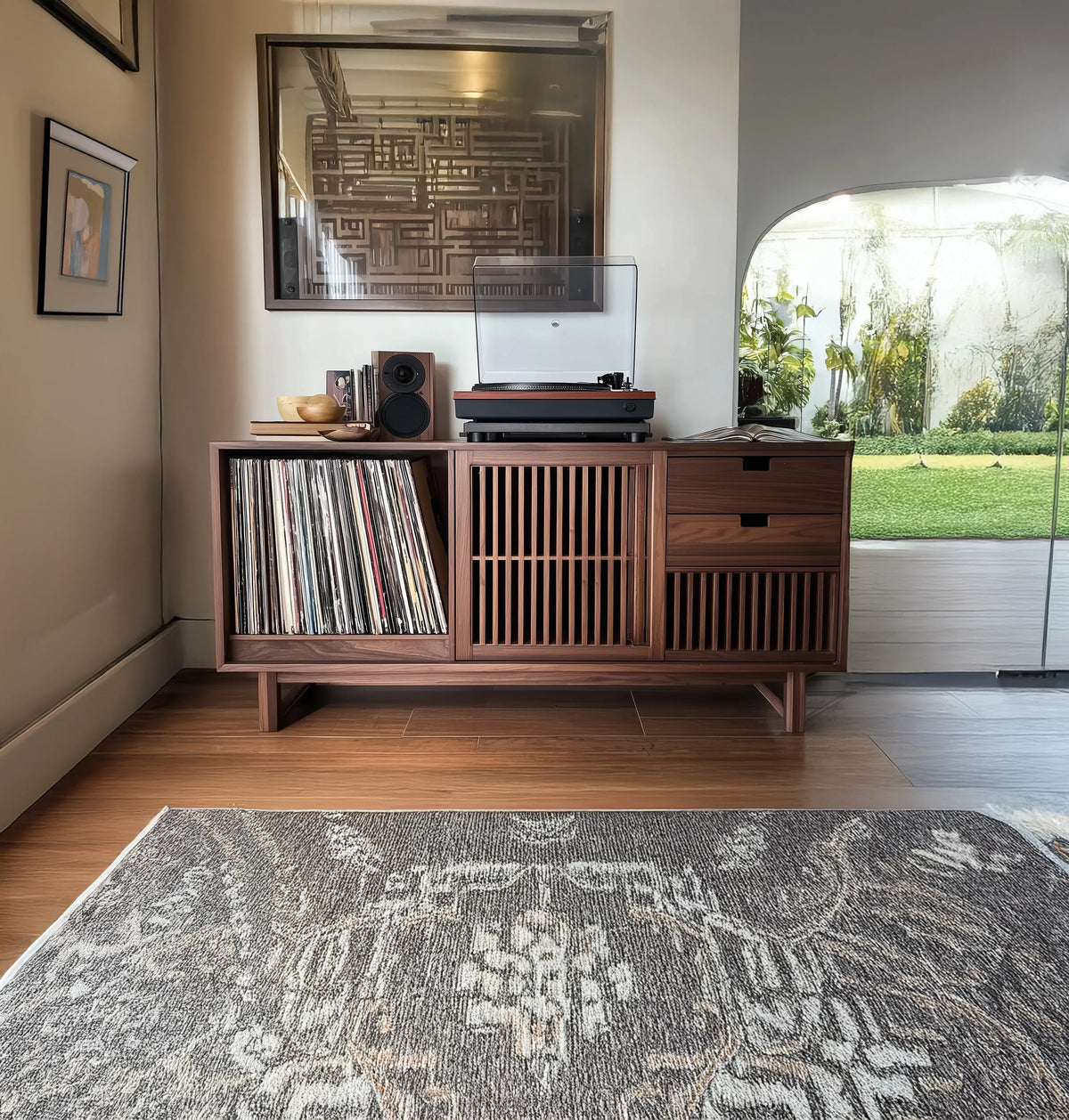 Wooden record player cabinet with vinyl records, speaker, and bowl in modern living room