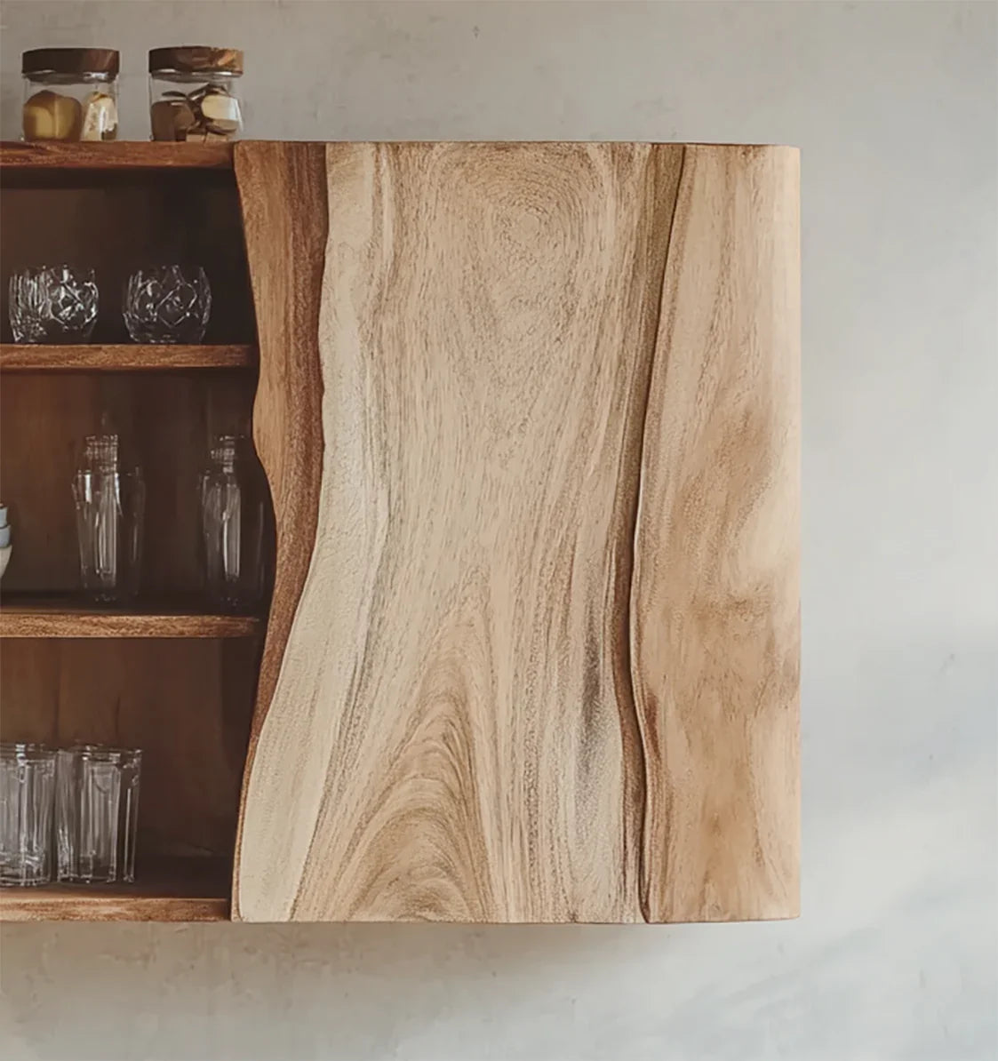 Close-up of natural wood kitchen cabinet door with open shelving and glassware inside