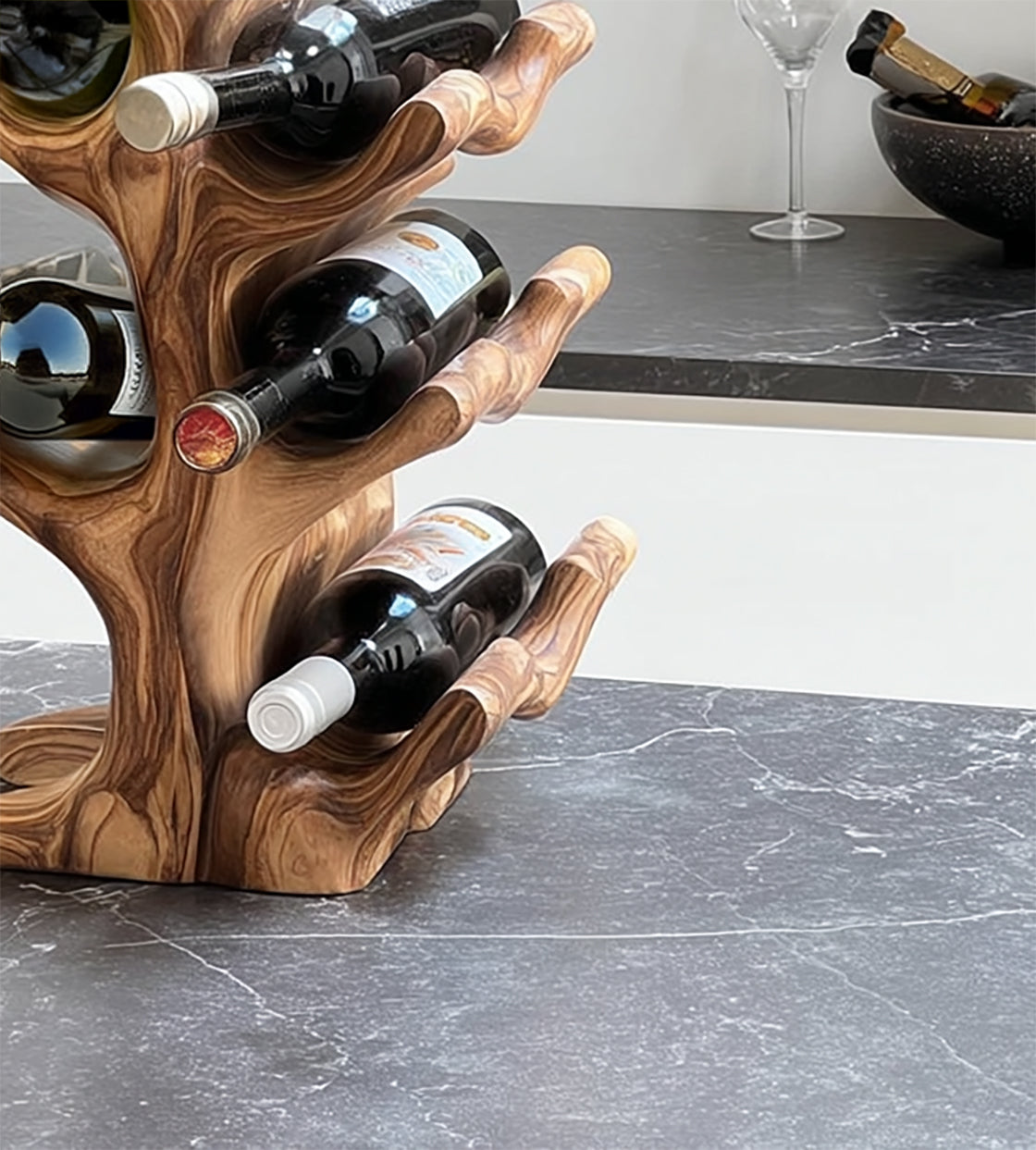 Modern wooden wine rack holding red wine bottles on a gray marble countertop