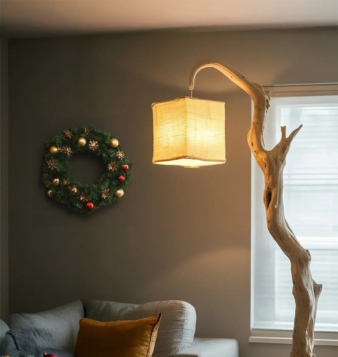Cozy living room with modern wooden floor lamp, glowing fabric shade, and festive Christmas wreath
