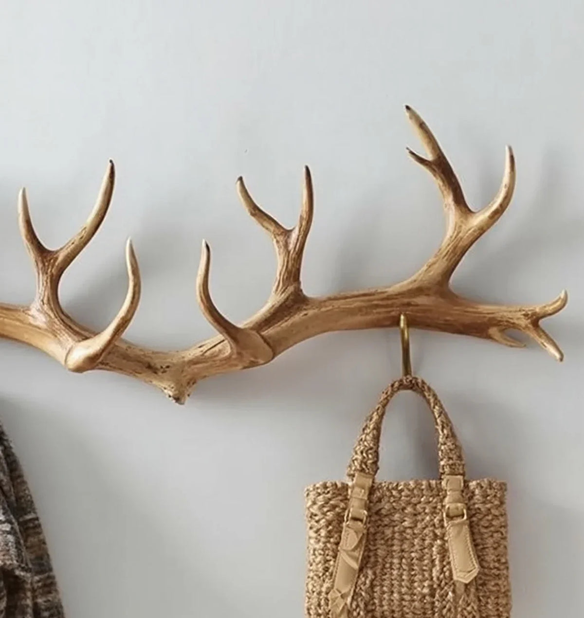 Wall-mounted wooden antler coat rack with woven bag hanging, rustic home decor