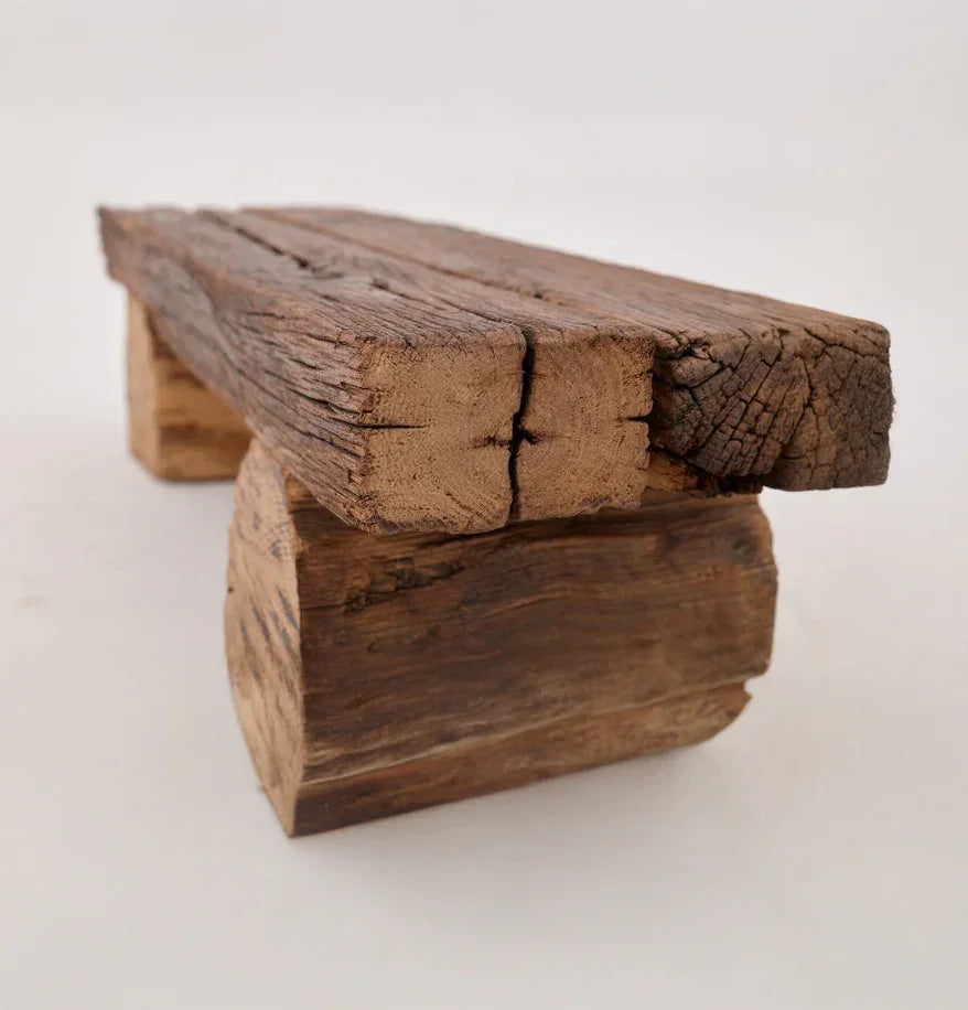 Rustic live edge solid wood bench with natural cracks and aged texture on a white background.