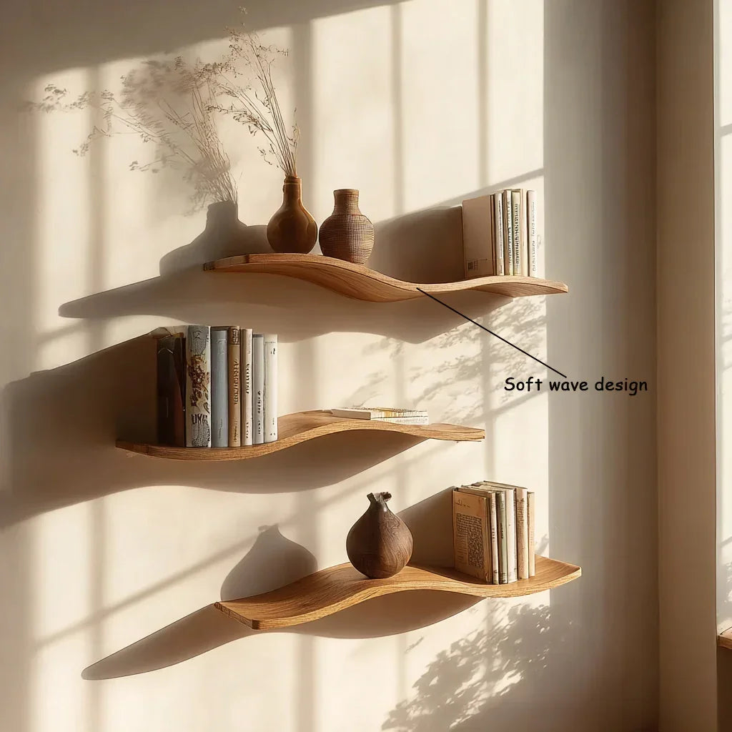 Solid wood floating shelves with soft wave design, displaying vases and books on a sunlit wall.