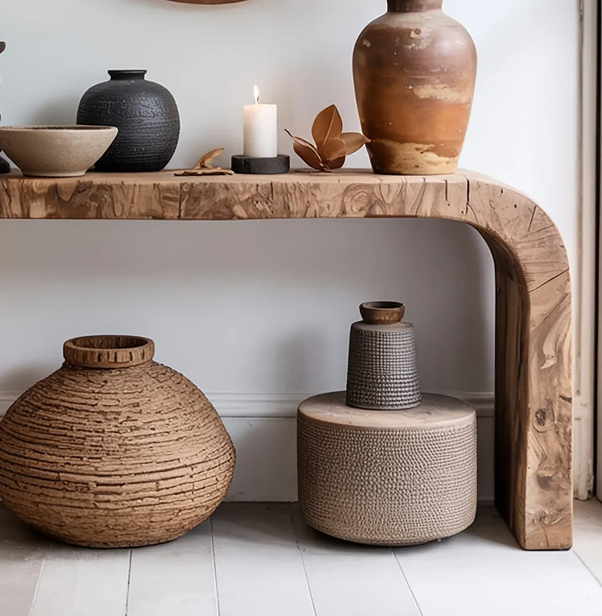Solid wood live edge console table with decorative pottery, candle, and textured vases