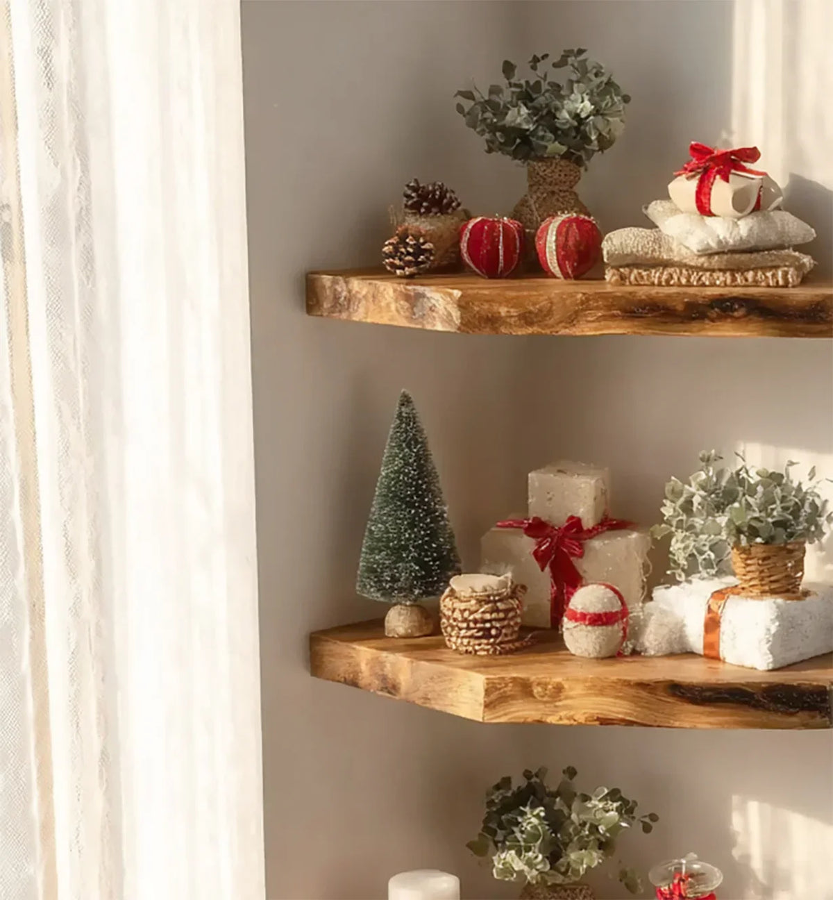 Rustic wooden shelves with Christmas decor including miniature tree, wrapped gifts, pine cones, and greenery