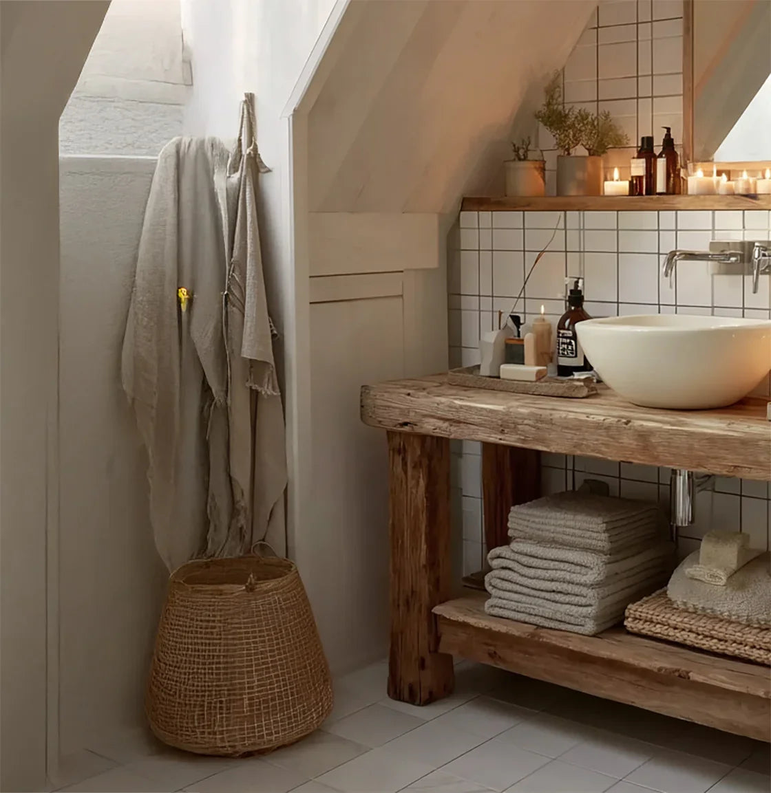 Cozy rustic bathroom with wooden sink vanity, stacked towels, candles, and potted plants