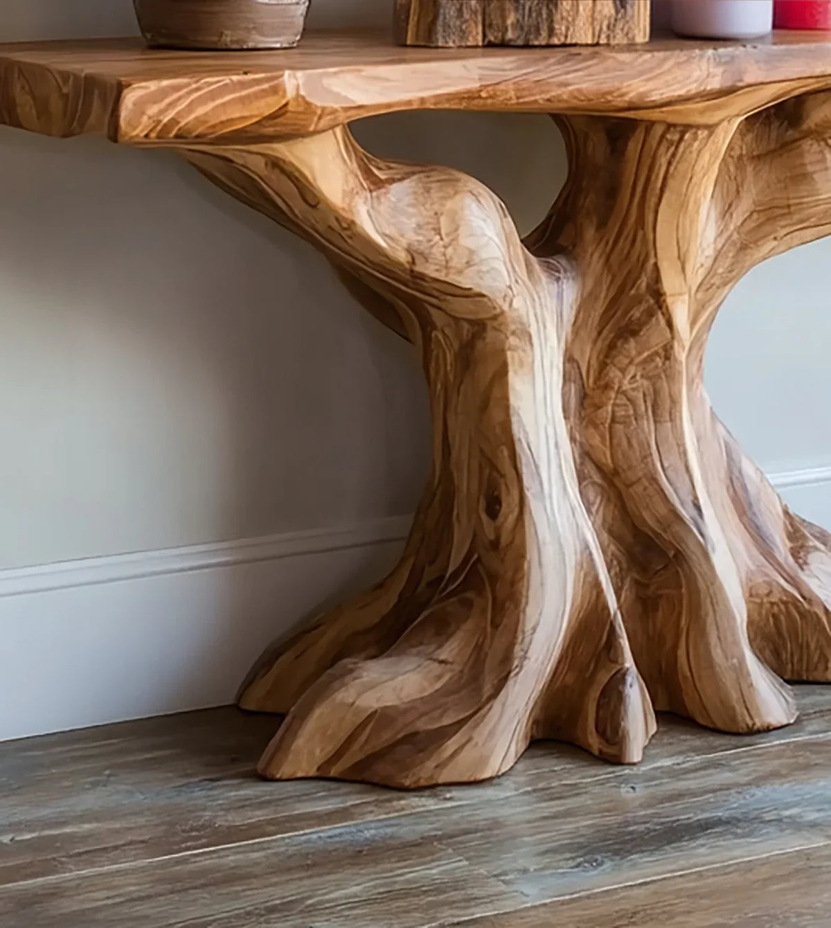 Natural wood table base carved to resemble roots on wooden flooring against white wall