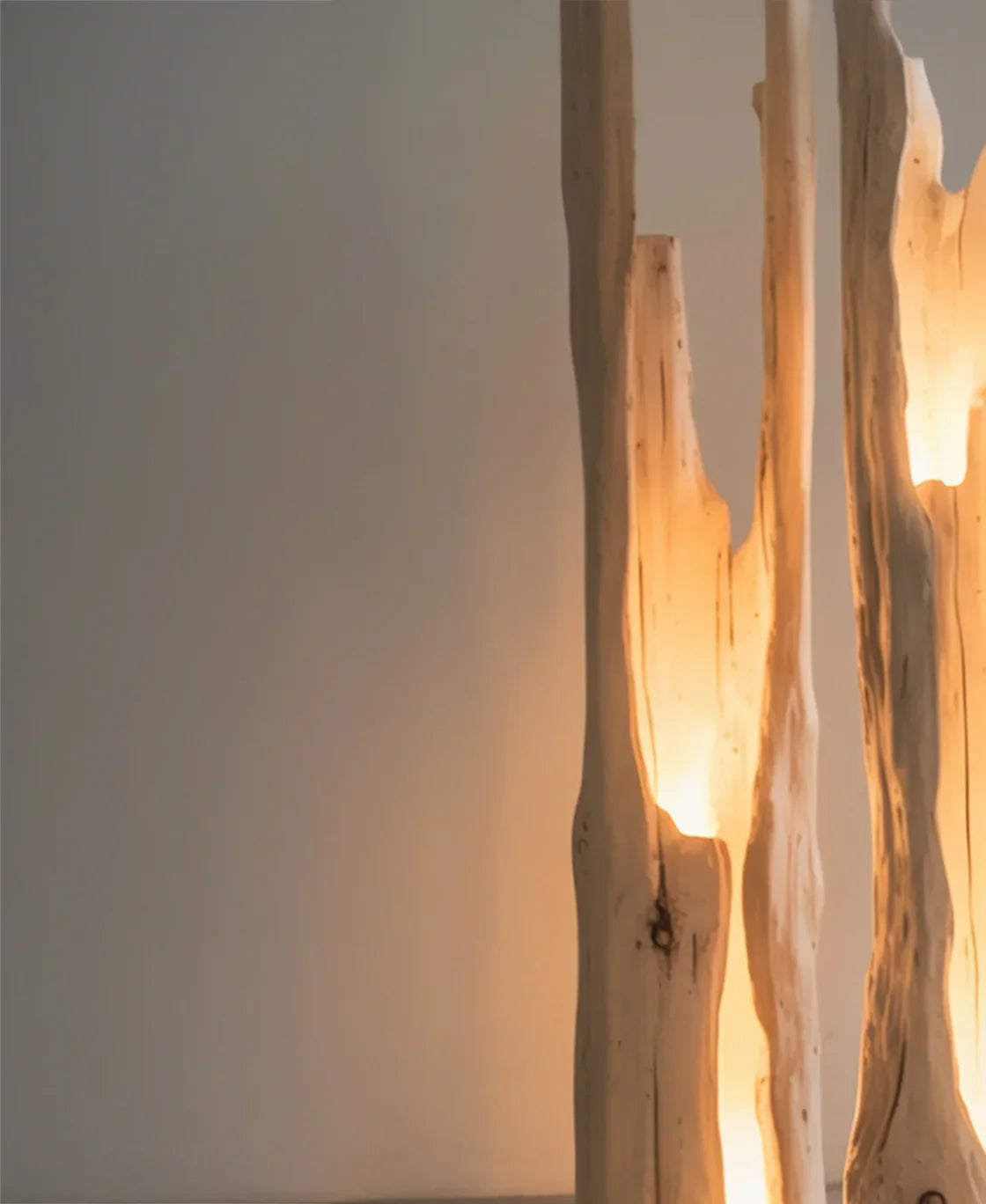 Natural wood floor lamps with warm lighting against a plain wall in modern interior