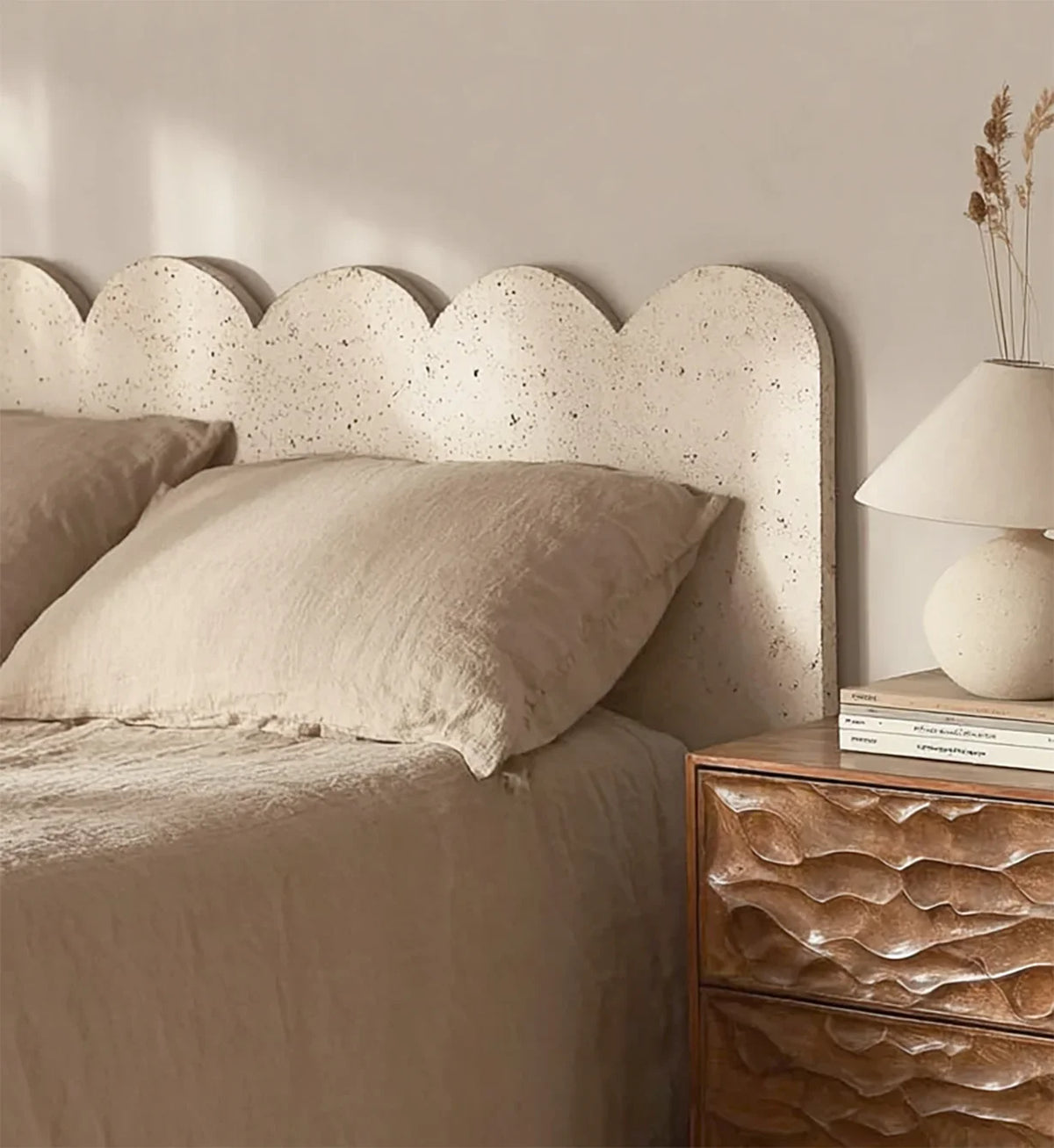 Scalloped textured headboard bed with beige linen, wooden nightstand, and modern lamp