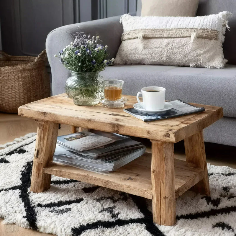 Rustic wooden coffee table with vase of wildflowers, tea, coffee cup, magazines under, in cozy living room