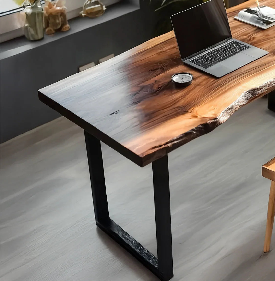 Live edge wooden desk with black metal legs, laptop, and gauge on light wood floor