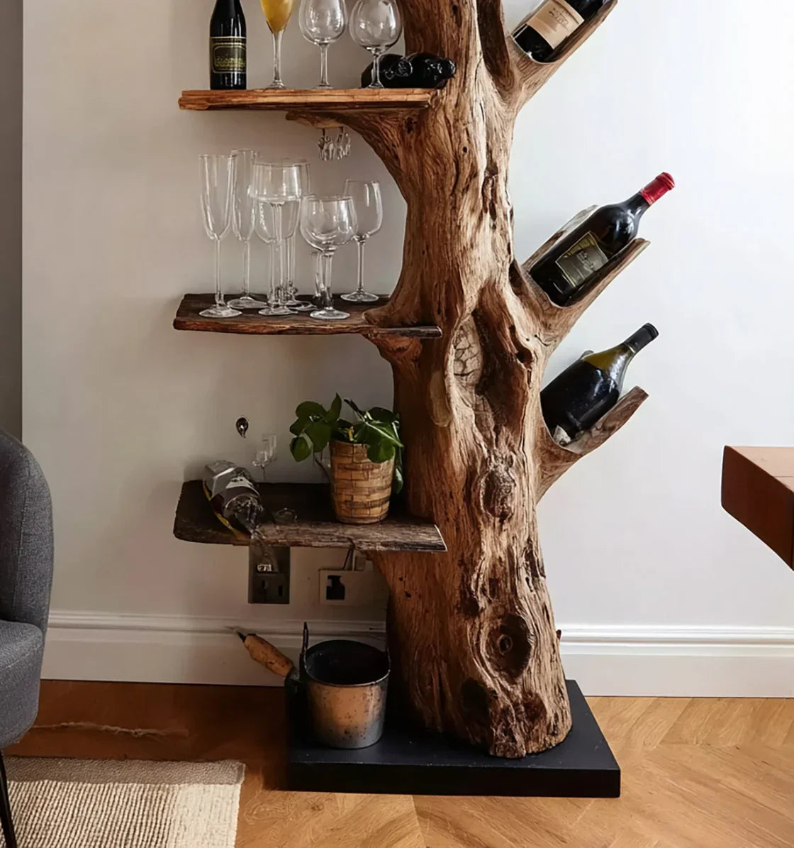 Rustic tree trunk wine rack with wooden shelves holding wine bottles, glasses, and a plant in a cozy room