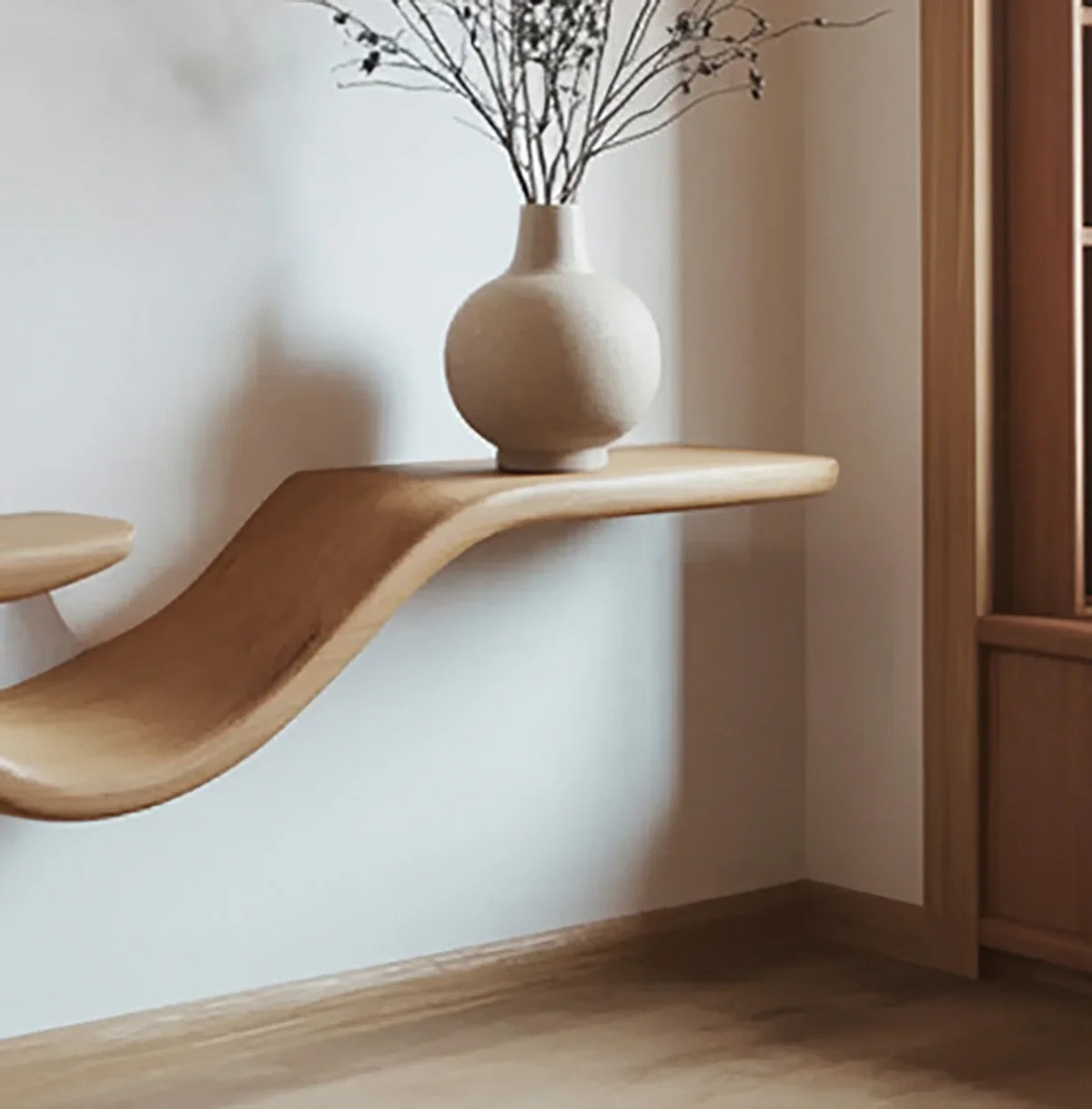 Curved solid wood floating shelf with vase in modern minimalist room