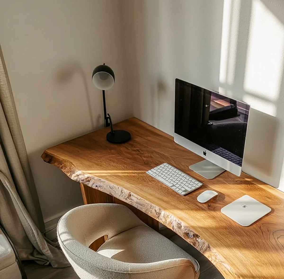 Live edge wood desk with computer, lamp, and modern chair in a sunlit home office