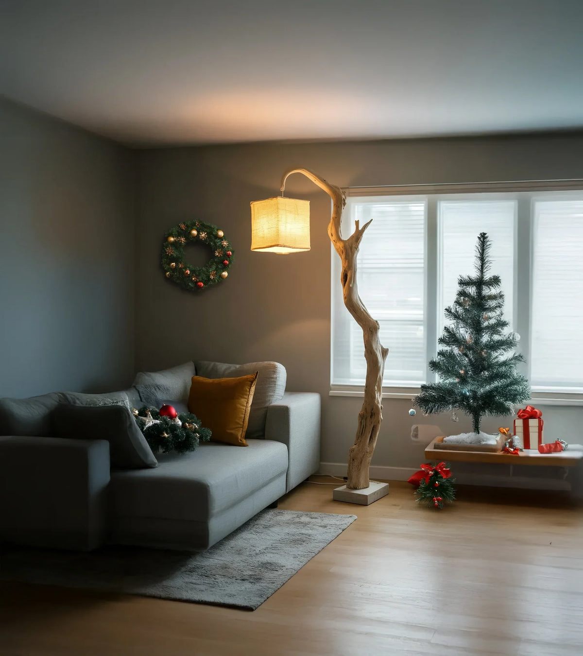Modern living room with gray sofa, wooden floor lamp, Christmas tree, wreath, and holiday decorations