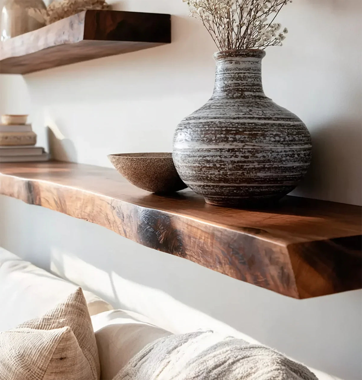 Solid wood live edge floating shelf with decorative vase, bowl, and books on wall above sofa