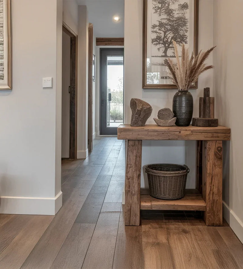 Rustic wooden console table in hallway with stone decor, vase with pampas grass, and framed tree artwork