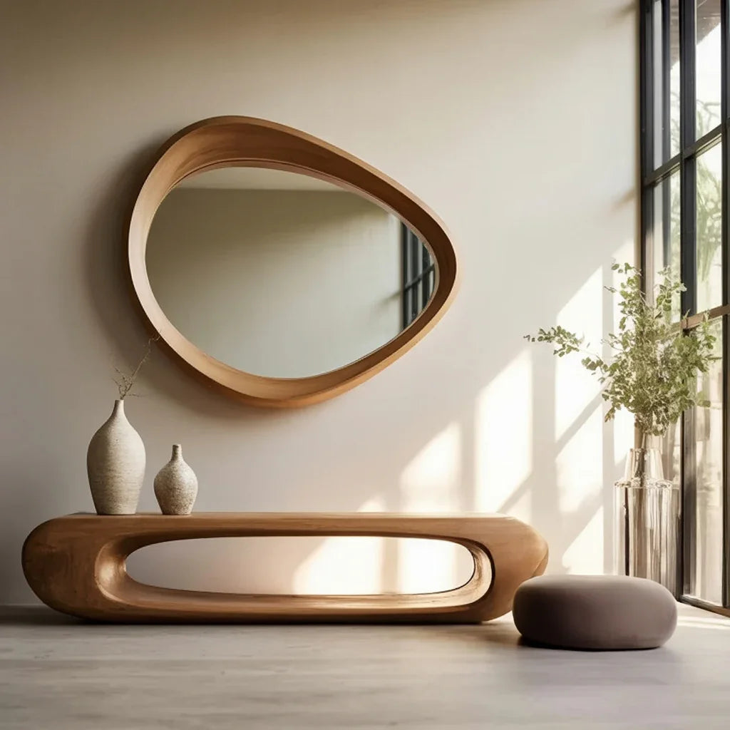 Modern entryway with solid wood console table, organic shape mirror, ceramic vases, and sunlight.