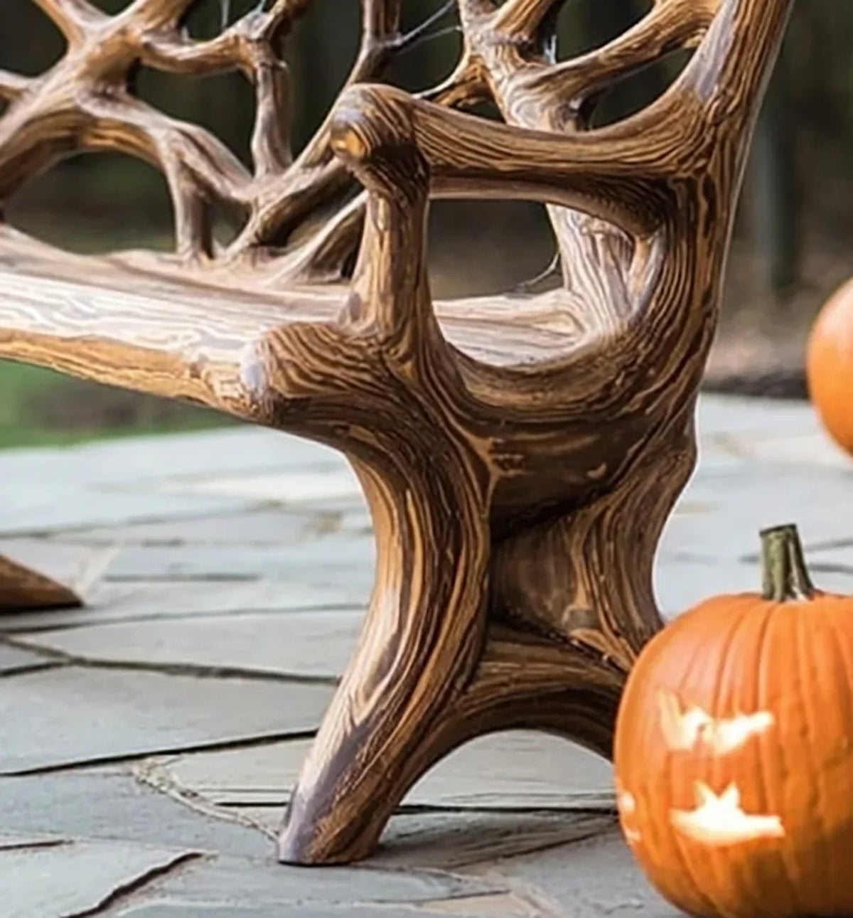 Close-up of rustic wood bench on stone patio with carved Halloween pumpkins nearby