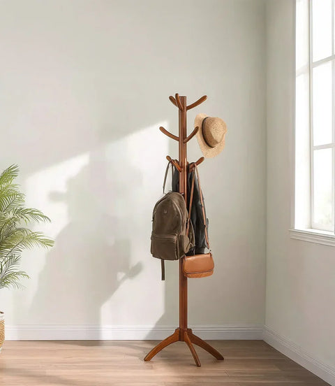Wooden coat rack with backpack, brown bag, and straw hat in sunlit minimalist room