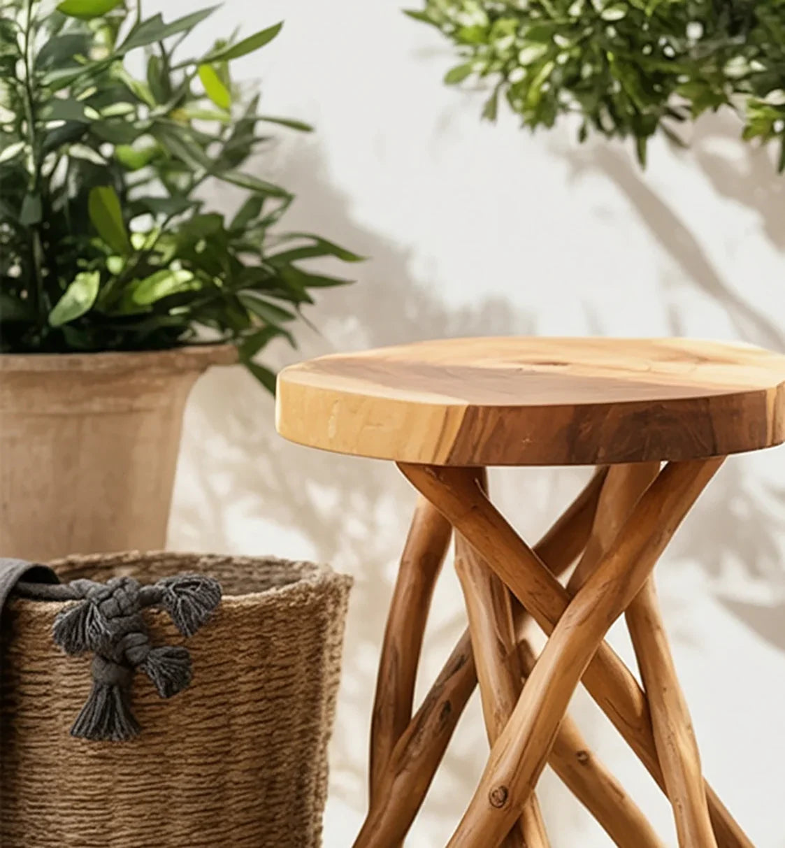 Natural wooden round stool with twisted legs beside woven basket and green potted plants