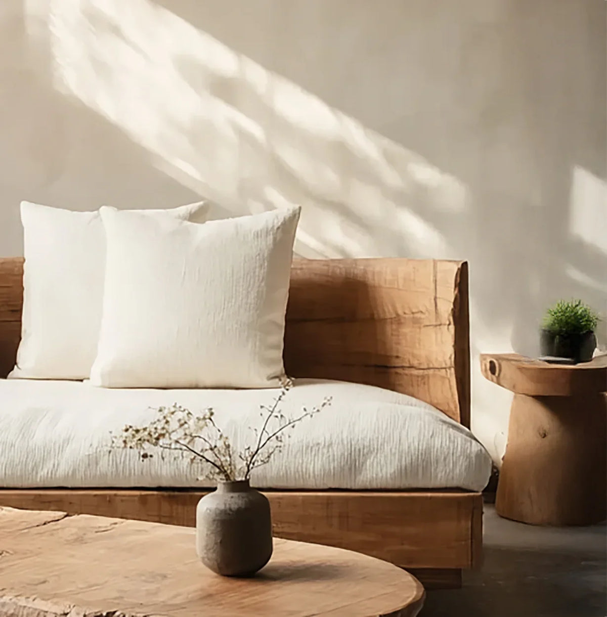 Solid wood live edge sofa with white cushions, rustic coffee table, and minimalist decor