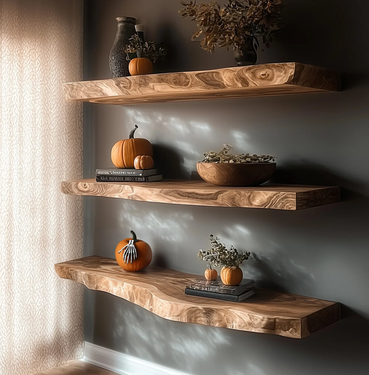 Floating wooden shelves with autumn decor including pumpkins, dried flowers, books, and a skeleton hand on pumpkin